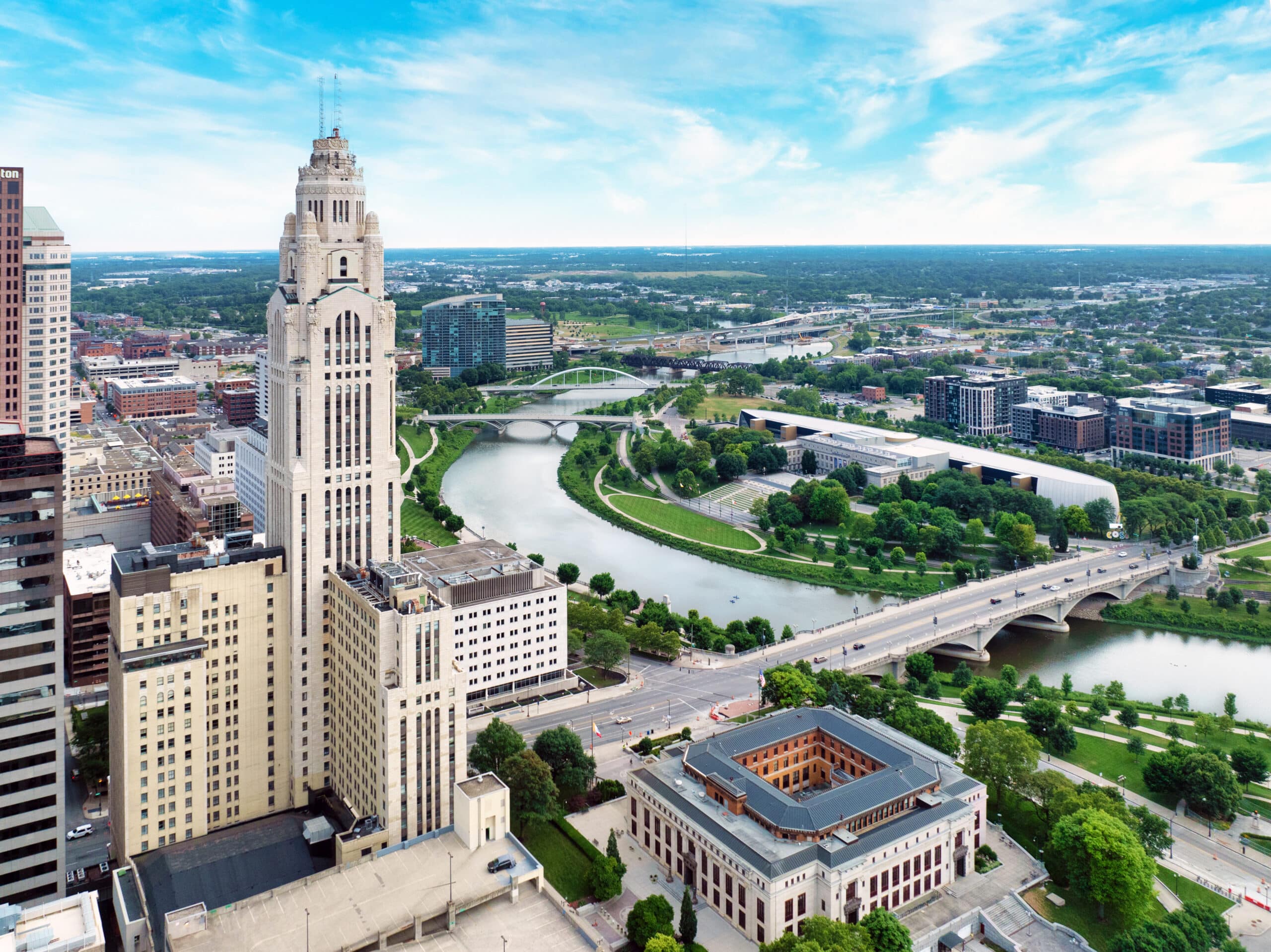 Aerial view of downtown Columbus, Ohio, featuring the LeVeque Tower, Scioto River, bridges, and cityscape—just a short drive from luxury apartments in Delaware—on a clear day.